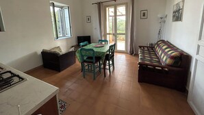 Um espaço compacto com área de refeições, sofá, televisão e cozinha.