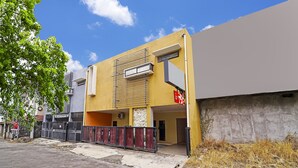 A modern building with a yellow facade, a gated entrance, and a clear blue sky. - OYO 91342 Tatti Inn Syariah (Depok)