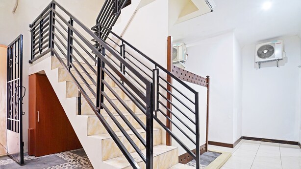 A staircase with black railings and beige steps, leading to a room with white walls and a tiled floor. - OYO 91342 Tatti Inn Syariah (Depok)