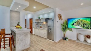 A modern kitchen with a central island, built-in appliances, and a large flat-screen TV mounted on the wall. - 2 Br Great Located Spacious Amazing Terrace (Tulum)