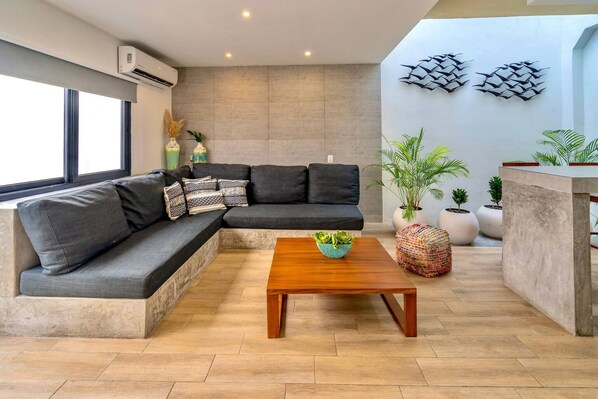 Una sala de estar moderna con un sofá modular, una mesa de centro de madera y plantas en macetas.