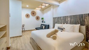 A modern bedroom with a large bed, a dark armchair, and a small table with decorative items. - 2 Br Great Located Spacious Amazing Terrace (Tulum)