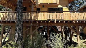 A wooden cabin with a balcony, surrounded by trees.