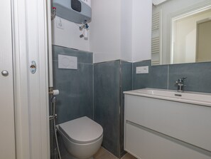 A bathroom with a toilet, a shower, and a sink.