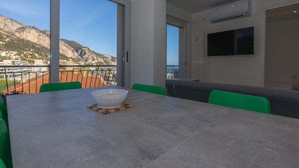 A dining area with a table, chairs, and a view of a mountainous landscape. - Calm 1BR Apt renovated with terrace and WiFi in Menton (Menton)
