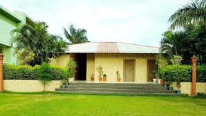 A two-story house with a tiled roof, a front porch with steps, and potted plants. - Hotel Riya Palace (Haldwani)