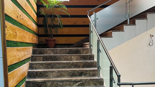 A staircase with a wooden wall and a potted plant. - Hotel Riya Palace (Haldwani)
