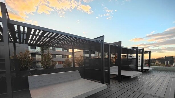 An outdoor deck with wooden flooring, built-in benches, and a pergola structure. - Modern 1-bedroom Unit in Dicksonnear Shops (Dickson)