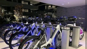 A row of bicycles parked in a modern indoor area with a brick wall and a balcony in the background. - Modern 1-bedroom Unit in Dicksonnear Shops (Dickson)