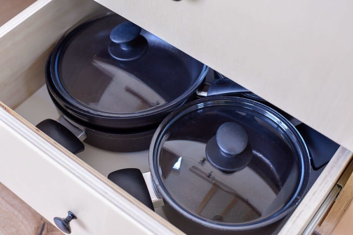 A drawer with two black pots with lids.