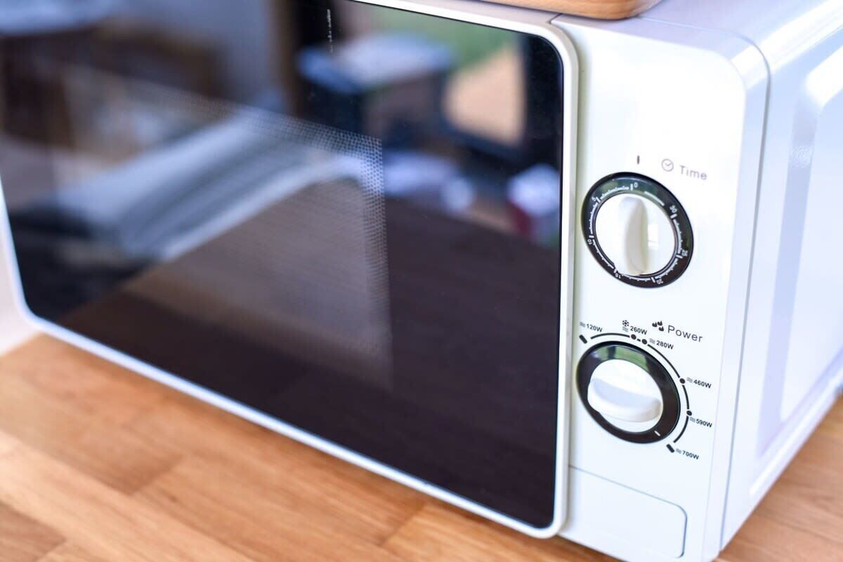 Un forno a microonde con display digitale, due manopole etichettate 'Tempo' e 'Potenza', e un indicatore della potenza.