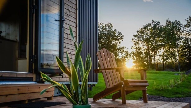 A wooden deck with a chair and a potted plant. - Böstebacken Tiny House by Tiny Away (Alingsås)