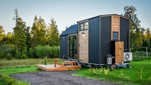 A compact, modern cabin with a large sliding door, a small deck, and a fan. - Böstebacken Tiny House by Tiny Away (Alingsås)
