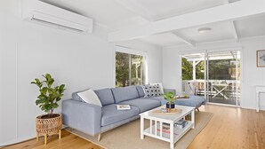 A modern living room with a grey sofa, a small white coffee table, and a potted plant.