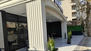 A building with a large glass facade and a sign that reads "SAMSUNG". There are two potted plants in front of the entrance. - Cam Suites (Kahramanmaras)