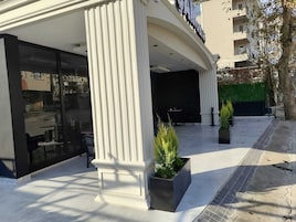 Um edifício com uma fachada de vidro ampla e uma placa com a inscrição "SAMSUNG". Há duas plantas em vasos na frente da entrada.