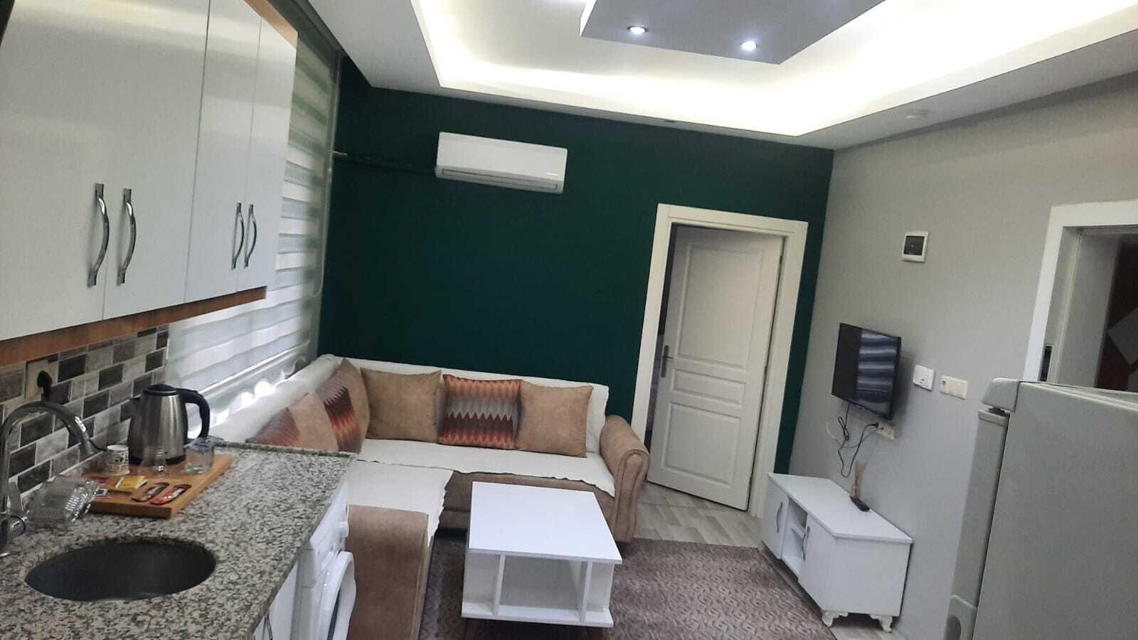 A compact kitchen with a built-in oven, a coffee machine, and a small dining area.