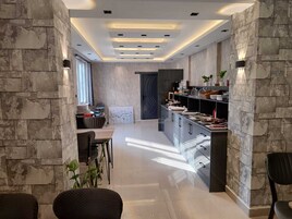 Cozinha moderna com ilha central, eletrodomésticos embutidos e parede decorada com pedra.