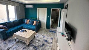A modern living room with a sectional sofa, a coffee table, a flat-screen TV, and a ceiling with recessed lighting. - Cam Suites (Kahramanmaras)