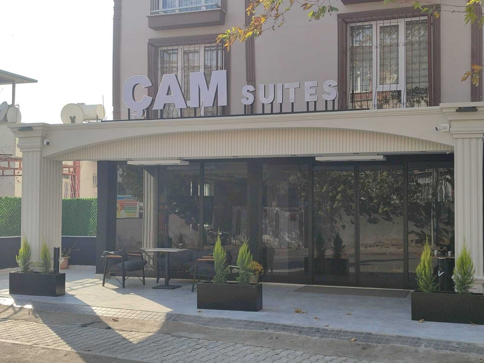 A hotel named "CAM SUITES" with outdoor seating and potted plants.