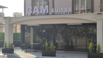 A hotel named "CAM SUITES" with outdoor seating and potted plants.
