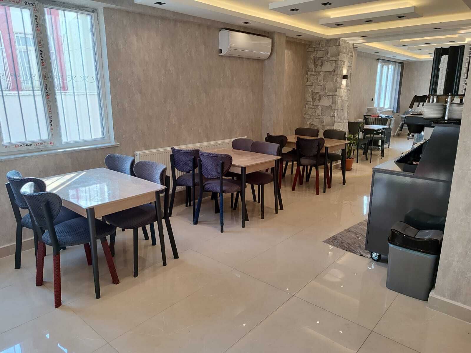 Un comedor moderno con varias mesas y sillas, un muro de acento de piedra y una zona de cocina con una parrilla.