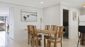 A dining area with a wooden table and chairs, a vase with dried flowers, and a beach-themed painting on the wall. - Bay Retreat in Cowes (Cowes)