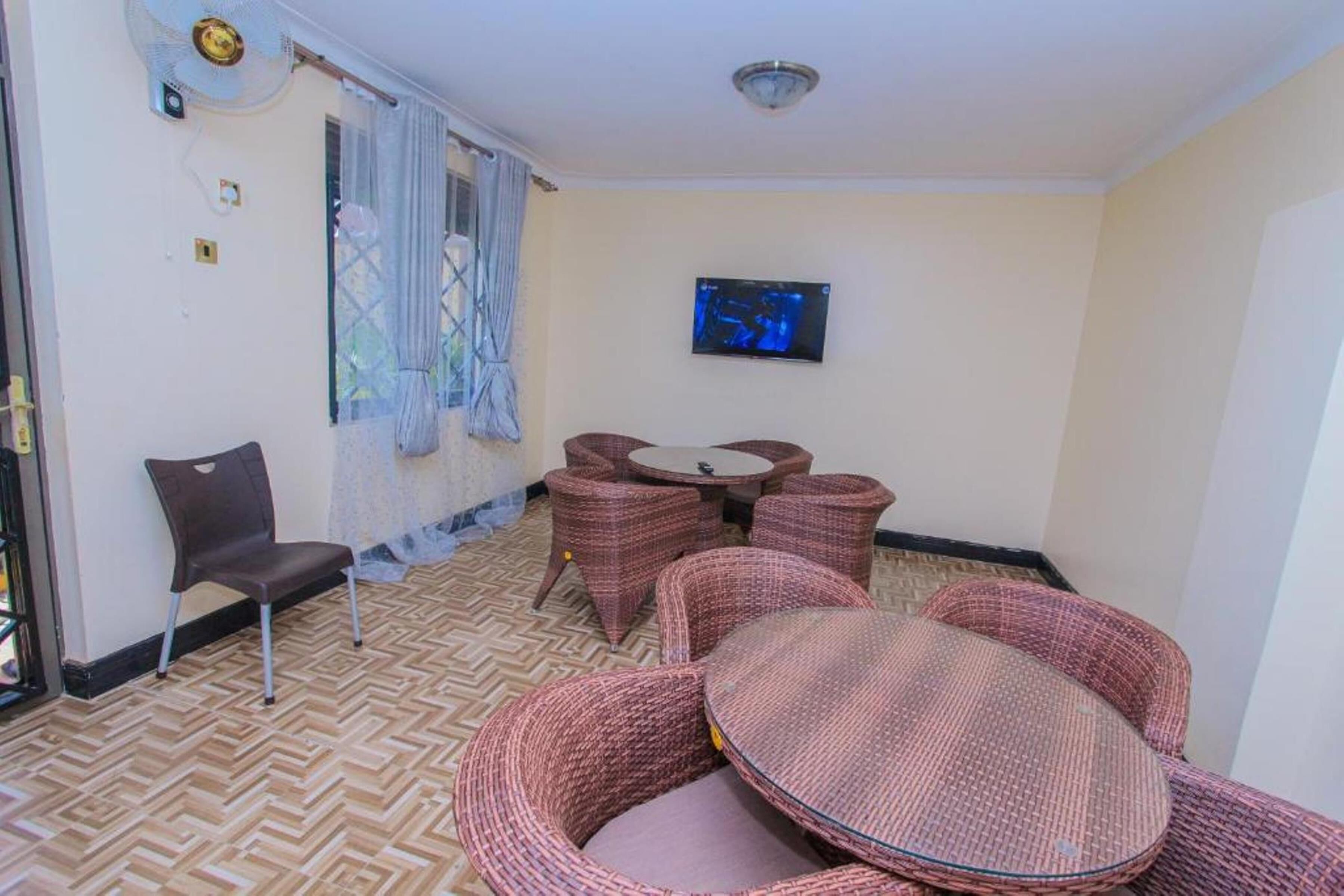 A room with wicker furniture, a television, and a patterned floor.
