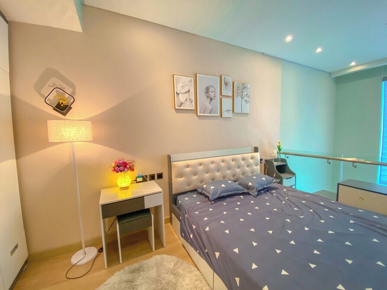Een moderne slaapkamer met een bed, nachtkastje, lamp en kunst aan de muur.