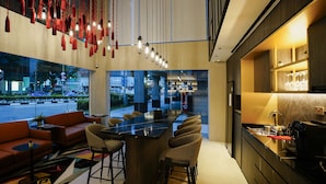 A modern bar area with a long counter, bar stools, and hanging red lanterns. - ST Signature Bugis Middle, SHORT OVERNIGHT, 11 hours: 8PM-7AM  (Singapore)