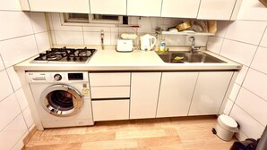 A compact kitchen with a gas stove, a built-in washing machine, a sink, and a microwave. - A Family House (Seoul)