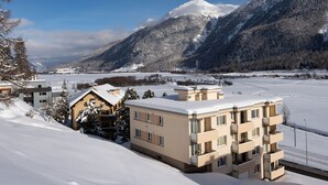 A snow-covered mountain landscape with a residential area featuring multi-story buildings with balconies. - Chesa Muntarütsch by Interhome (Samedan)