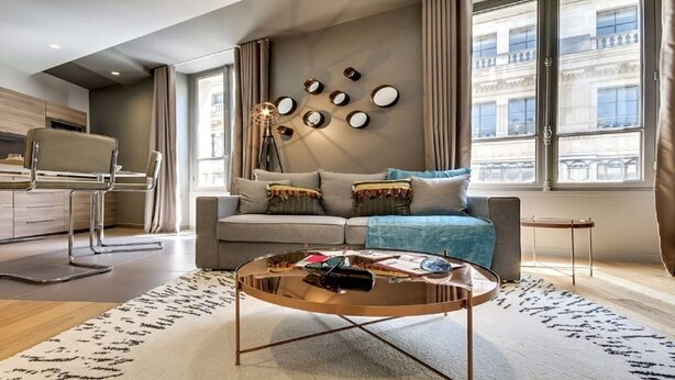 A modern living room with a sofa, coffee table, and a dining area with a chair and table. - The magnificent residence in the heart of 8th district- rue de la Boetie (Paris)
