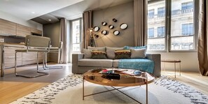 A modern living room with a sofa, coffee table, and a dining area with a chair and table. - The magnificent residence in the heart of 8th district- rue de la Boetie (Paris)