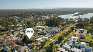 An aerial view of a residential area with houses, roads, and a beach. - Kingston Gardens by Experience Jervis Bay (Huskisson)