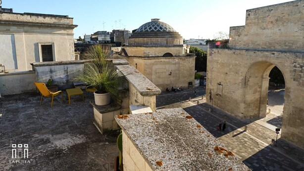 A rooftop terrace with stone flooring, a potted plant, and yellow chairs. - La putea suite (Lecce)