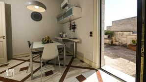 A compact room with a dining table, chairs, a clock, and a built-in air conditioning unit. - La putea suite (Lecce)
