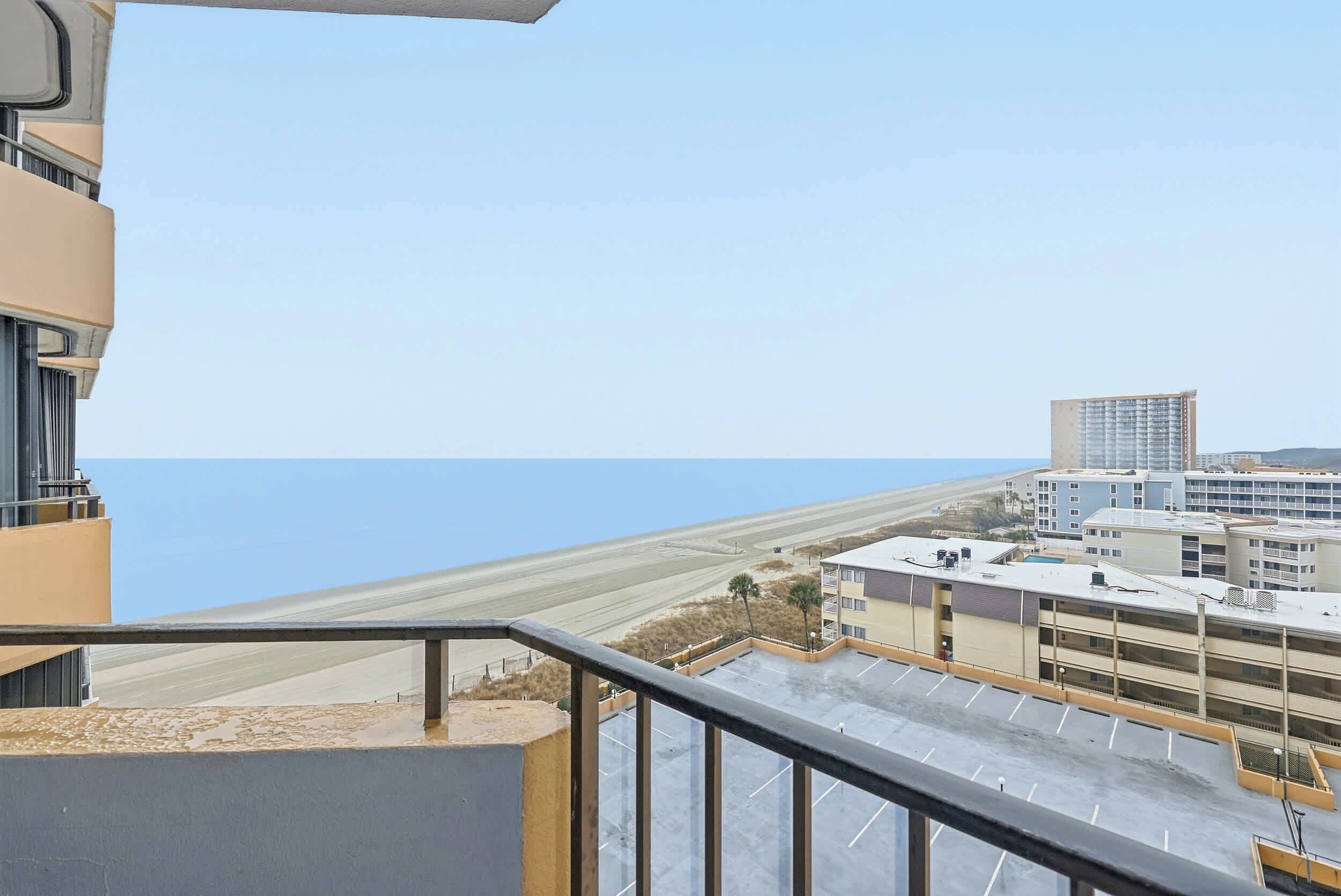 Vista desde un balcón sobre un estacionamiento y una playa.