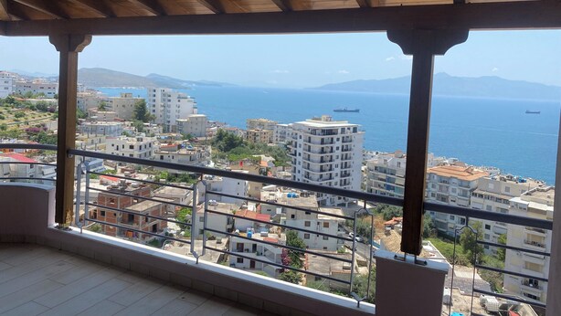 Un balcón con vistas a una ciudad costera, que incluye edificios y el mar.