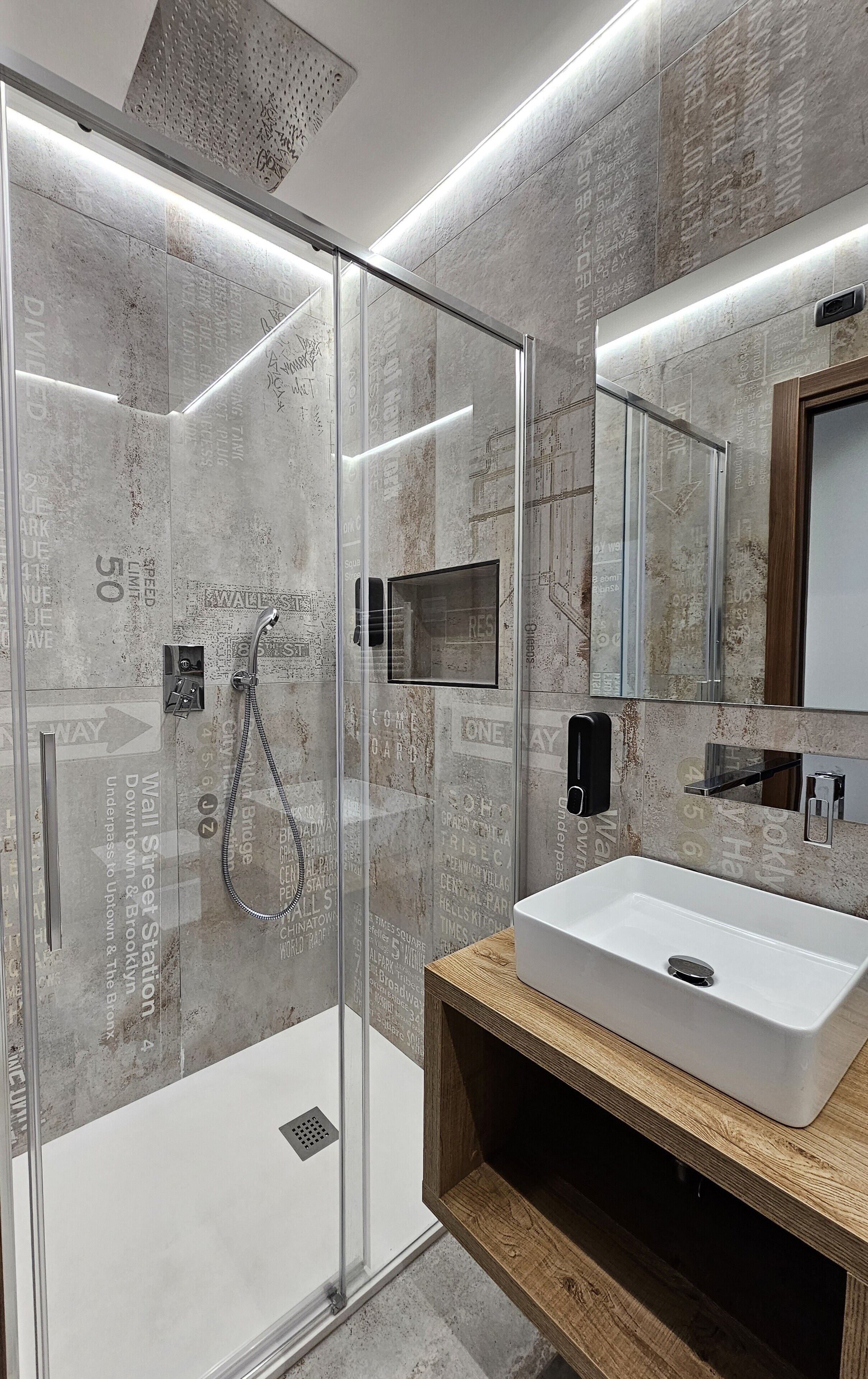 Un baño moderno con ducha de vidrio, lavamanos blanco y espejo con marco de madera.