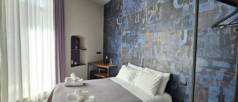 Una habitación de hotel moderna con una cama grande, un escritorio y una pared decorada con arte abstracto.