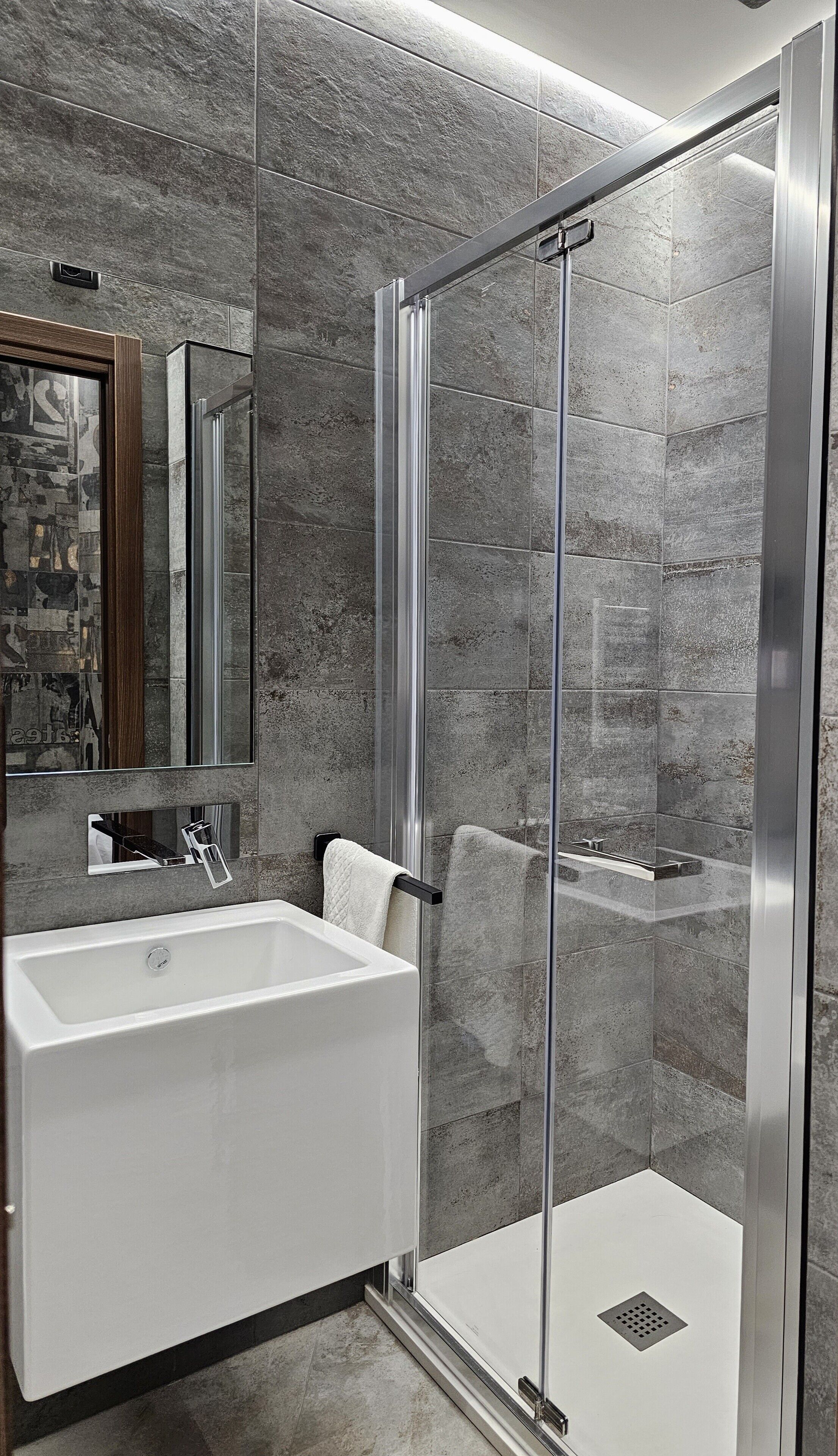 A modern bathroom with a large white bathtub, a glass-enclosed shower, and a mirror with a wooden frame.