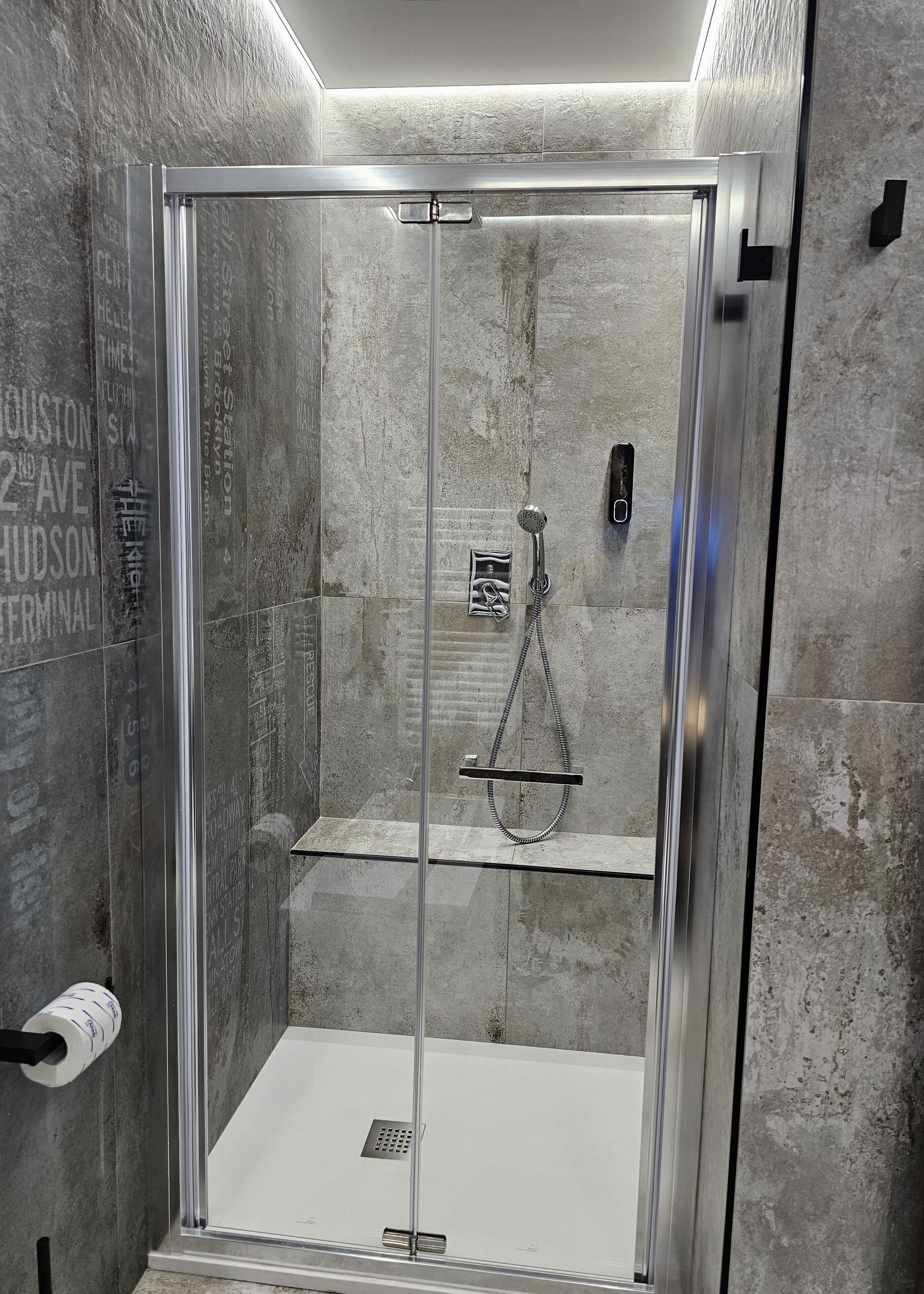 Une douche moderne dotée d’une porte en verre, d’un pommeau de douche à main et d’un porte-serviettes.
