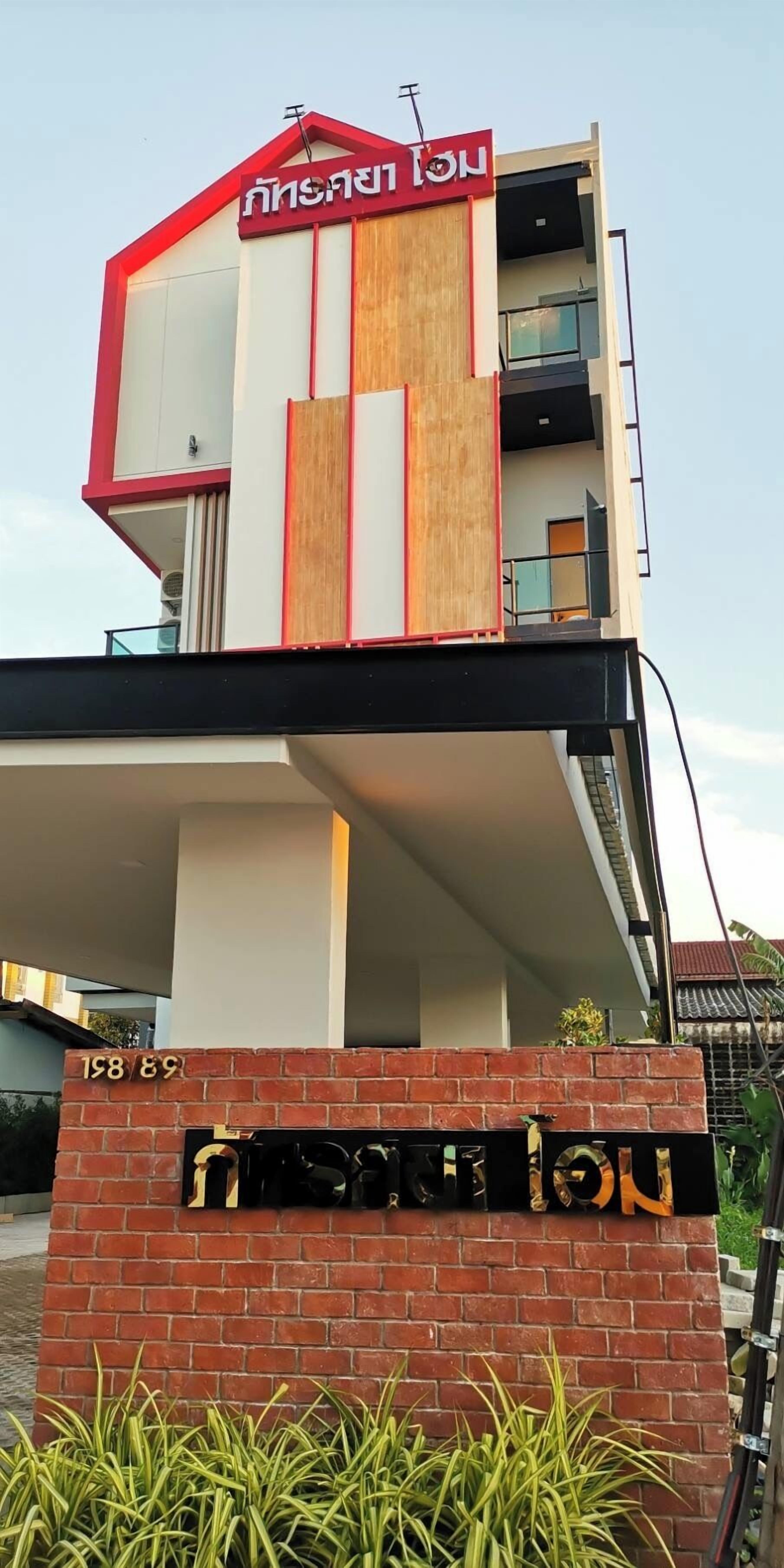 A modern building with a red and white facade, a wooden panel, and a balcony.