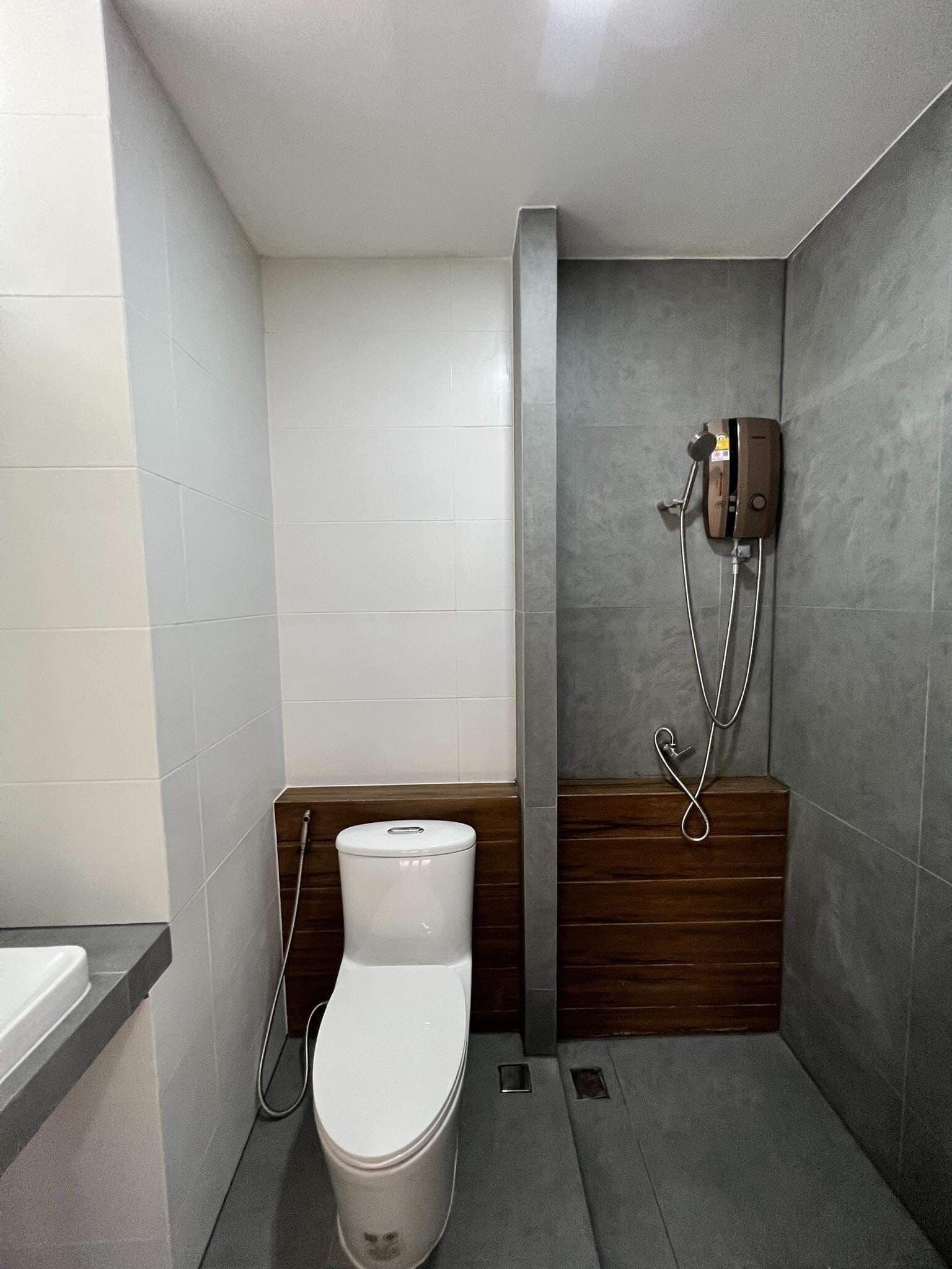 A compact bathroom with a toilet, a shower, and a towel rack.