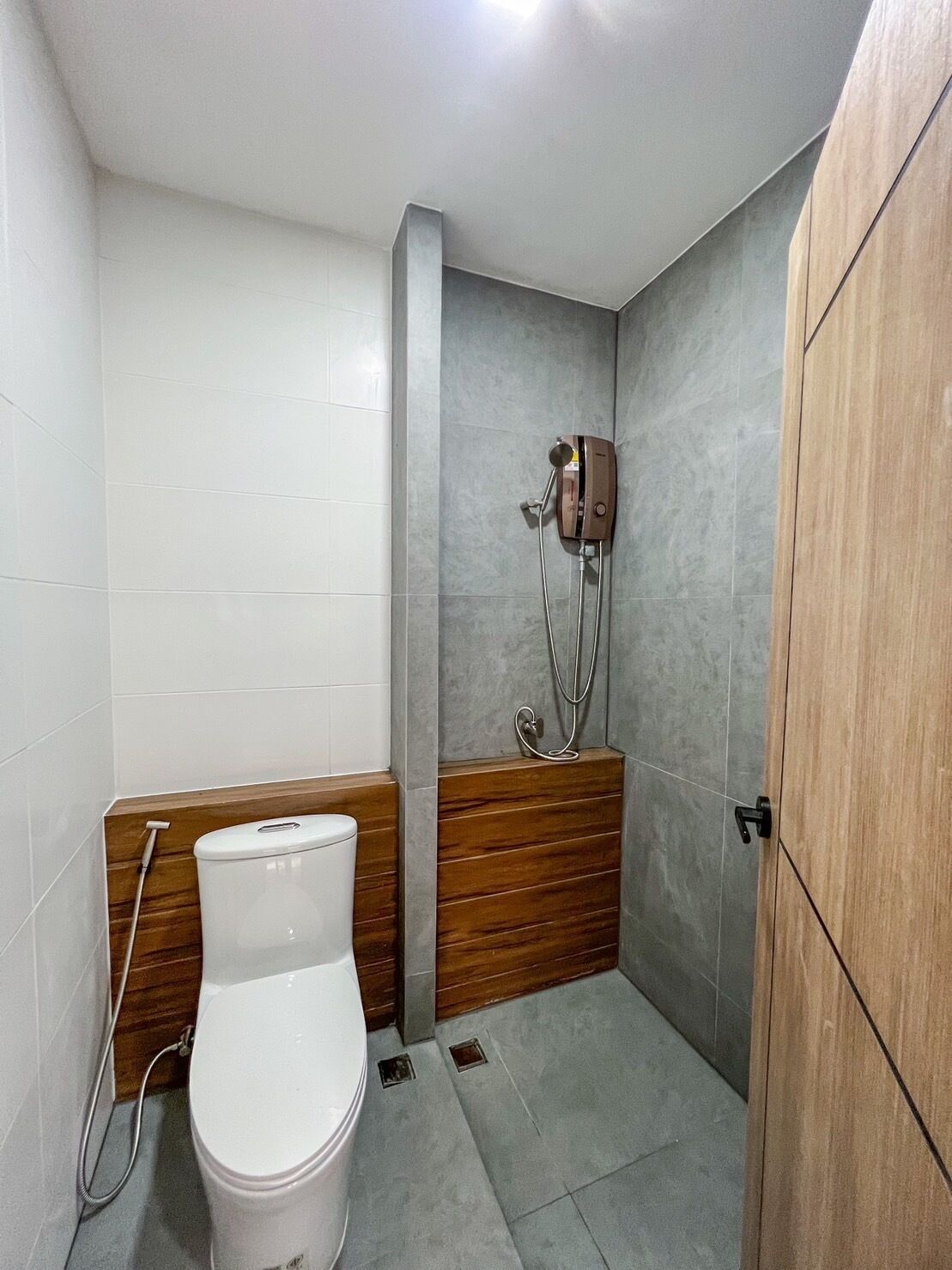 A small bathroom with a toilet, a shower, and a wooden vanity.