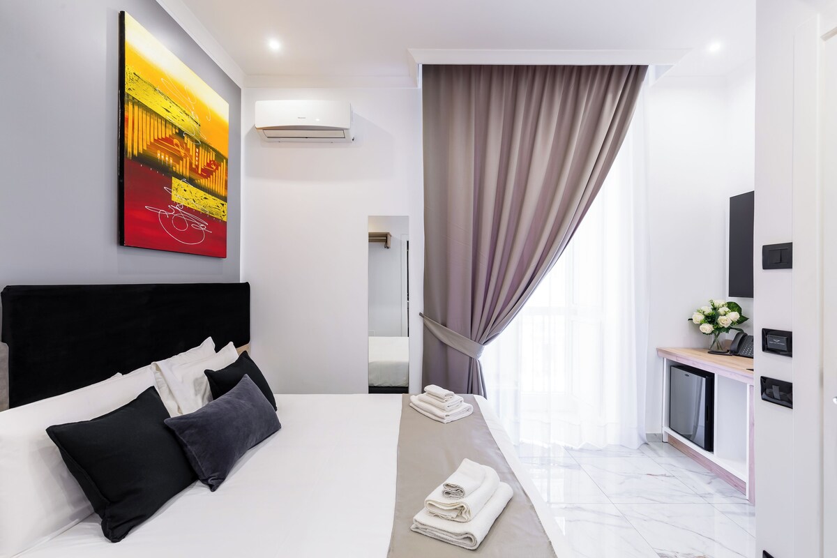 Ein modernes Hotelzimmer mit einem großen Bett, einem Flachbildfernseher, einem Schreibtisch und einem Bild an der Wand.