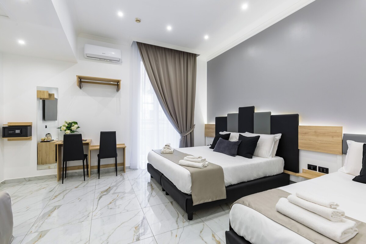A modern hotel room with a large bed, a desk, and a chair.