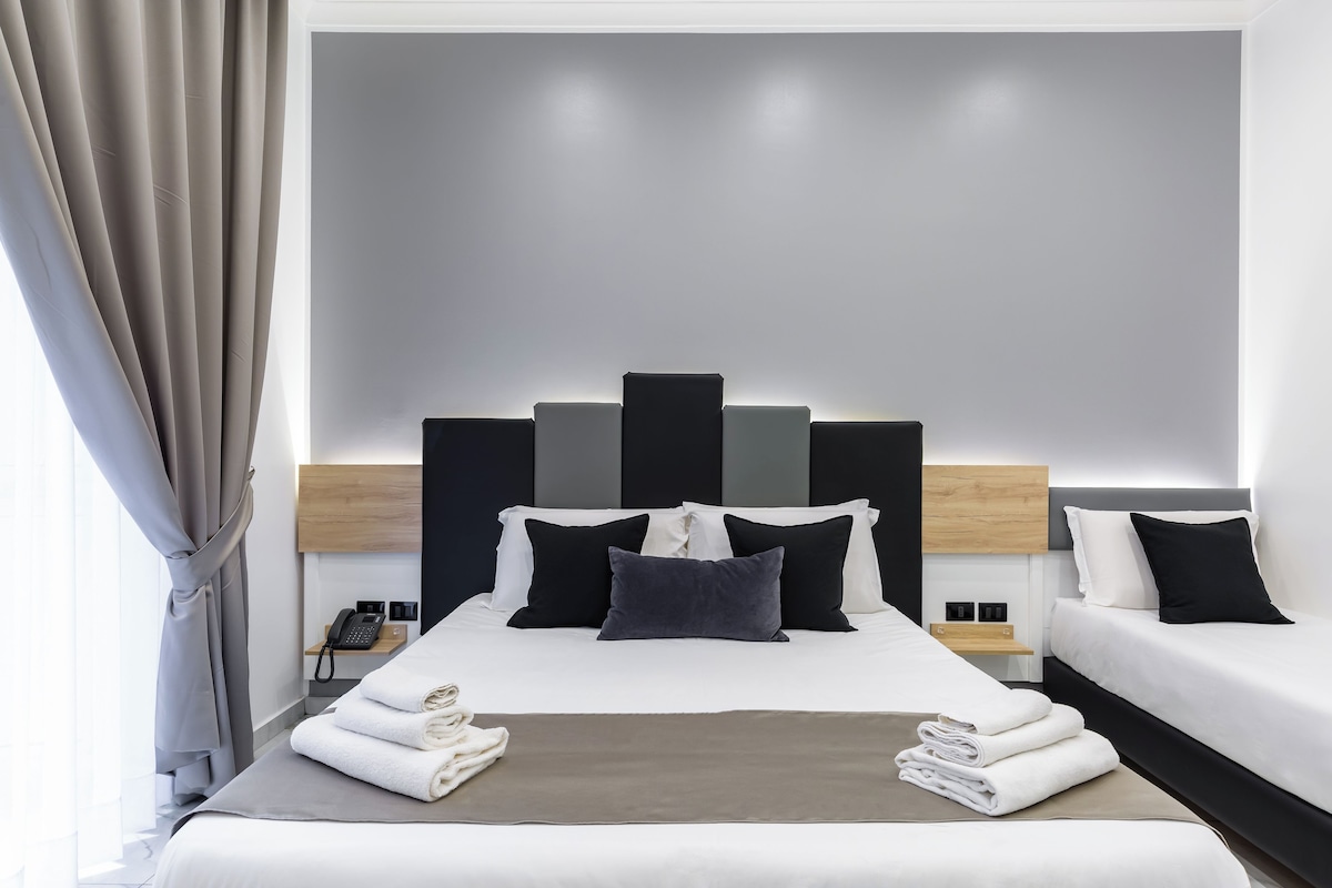Una camera d'albergo moderna con un letto grande, due comodini, una lampada da comodino e un telefono.
