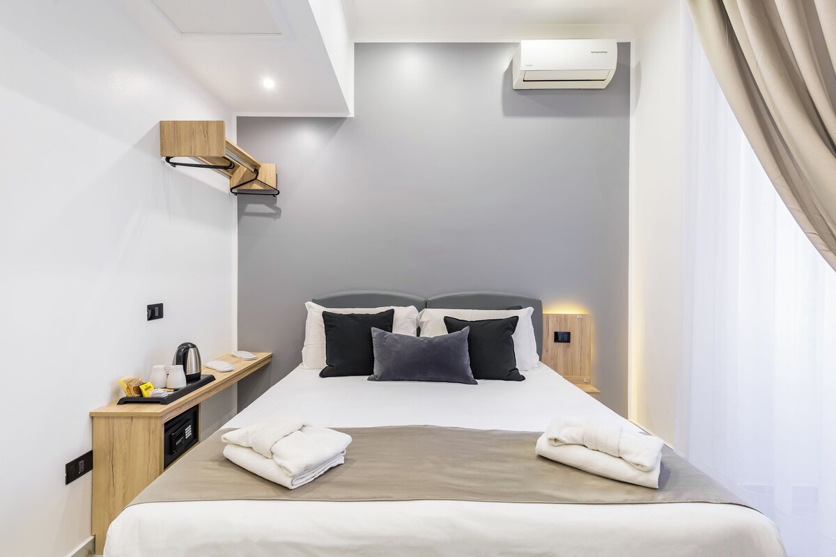 Una moderna camera d'albergo con un letto, un comodino e un condizionatore d'aria.